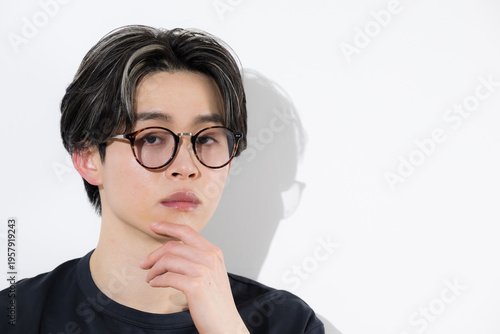 A close-up shot of a handsome young man with a stylish, beauty-focused look, wearing glasses (sunglasses) and looking directly at the camera