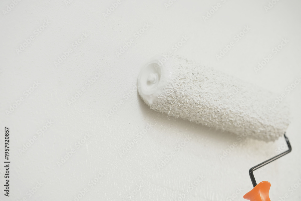 Obraz premium Roller Brush Painting, Worker painting on surface wall Painting apartment, renovating with white color paint. Leave empty copy space to write descriptive text beside. 
