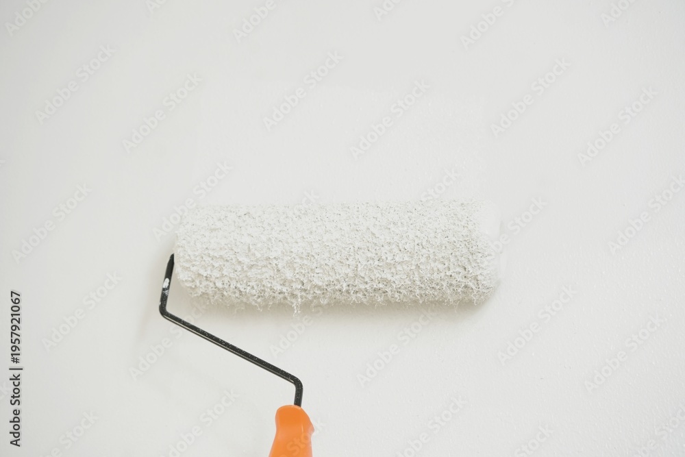 Fototapeta premium Roller Brush Painting, Worker painting on surface wall Painting apartment, renovating with white color paint. Leave empty copy space to write descriptive text beside. 