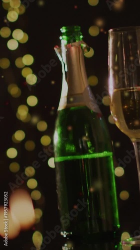 Green champagne bottle sitting on bar, torn foil causing confetti and bokeh flickering for events