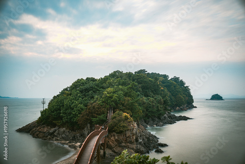 Wooden bridge leading to a lush green island in South Korea.