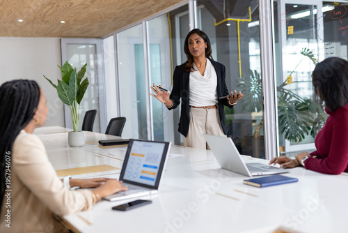 Diverse women team presenting sales figures on whiteboard in meeting room with marker, copy space