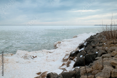Frozen Rocky Shoreline With Ice Floes and Overcast Sky Along Winter Lake Coastline