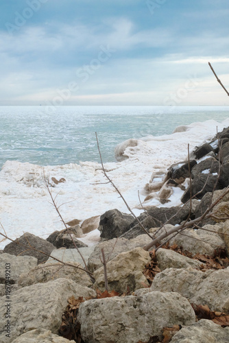 Winter Frozen Lake Shoreline With Rocky Coast, Ice Formations and Overcast Sky in Quiet Landscape
