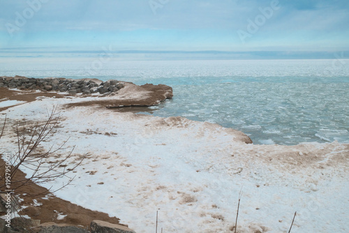 Frozen Shoreline and Icy Sea Under a Pale Winter Sky Along a Quiet Coastal Landscape