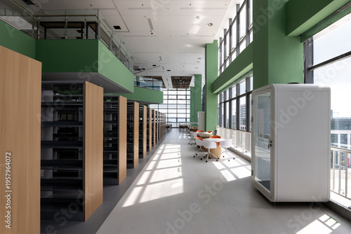 Modern library with green bookshelves, sunlit reading area and clean interior design