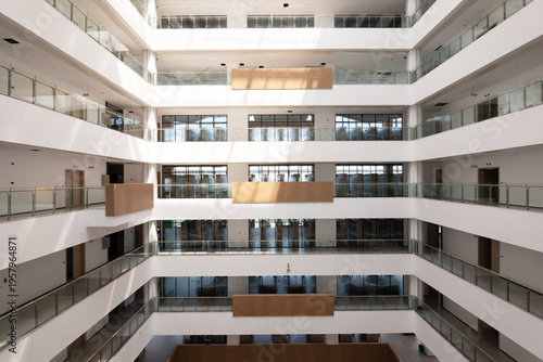 Fotografie Modern multi-story office building atrium with glass railings and wooden accents