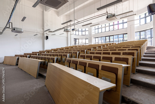 Quadro su tela Empty modern lecture hall with wooden desks and chairs arranged in tiered rows