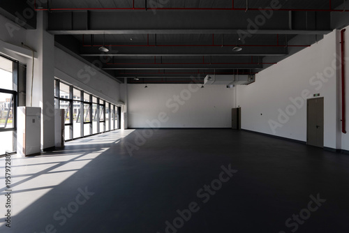 Tableau sur toile Spacious industrial-style factory interior with exposed ceiling pipes and large