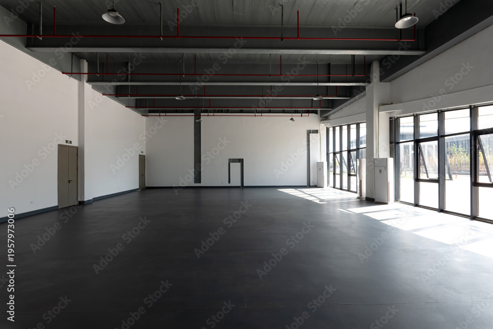 Obraz premium Spacious industrial-style factory interior with exposed ceiling pipes and natural light