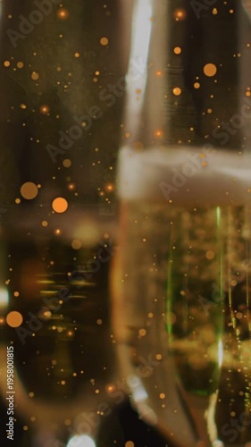 Vertical video: Rising bubbles urging champagne flutes moving center, specks drifting for warm glow