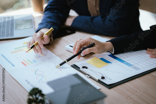 Business professionals discussing a house model with documents and calculator on a desk, representing real estate planning, property investment, and home buying consultation.