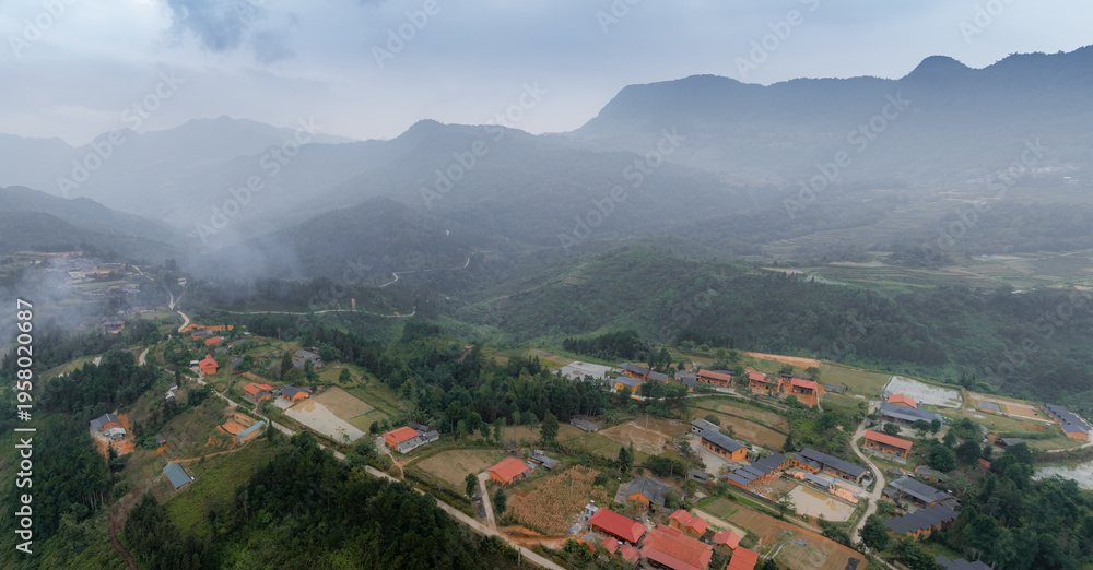 Obraz premium An aerial view shows the rural village of Quan Ba, Ha Giang, Vietnam, nestled in a valley surrounded by lush green mountains on an overcast day. ,