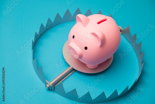 Piggy bank in trap on blue background. Financial scam or fraud, savings in danger, high interest rate loan, high risk investment, financial trap, untouchable savings, money literacy and so on concept.