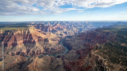 Vast arid canyon landscape with winding river carved through colorful rock formations under a blue sky
