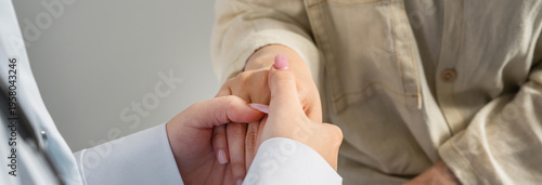 The doctor is empathizing with the patient, holding his hand.