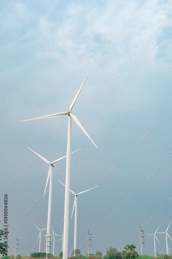 Fototapeta premium Low angle view of wind turbines against soft blue sky with minimal composition, representing clean renewable energy and modern sustainable power infrastructure.