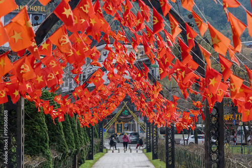 Tableau sur toile A woman walks along a path decorated with Vietnamese flags in Sapa, Lao Cai, Vietnam