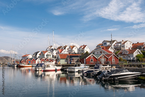 Boats and waterfront houses in Åstol harbour, Bohuslän, west coast Sweden, with red boathouses on quay