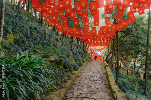 Quadro em tela A tourist walks along a stone path decorated with communist flags in Ham Rong Park, Sa Pa, Lao Cai, Vietnam