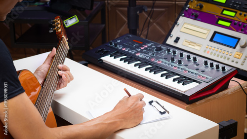 male musician writing a hit song by acoustic guitar in home studio. songwriting concept