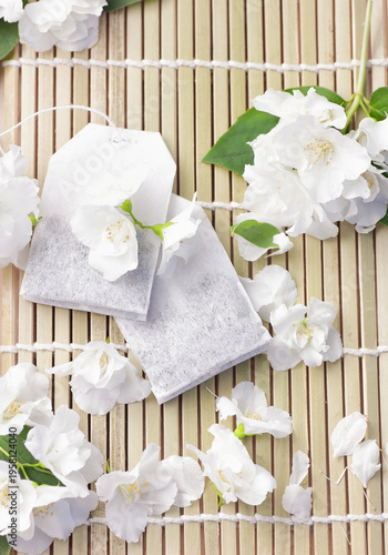 Jasmine floral teabags and fresh flowers and green leaves on asian background, closeup, natural medicine and naturopathy concept