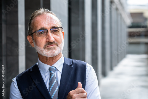 Confident mature Caucasian businessman giving thumbs up portrait in modern city with formal suit and glasses