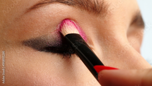 фотографія Make-up artist applies makeup to the upper eyelid, close-up