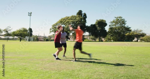Four pairs of trainers sprinting across manicured grass field, passing oak tree and floodlight pole
