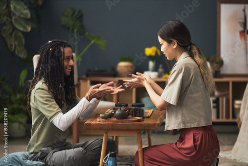 Canvastavla Young adult Asian woman and young adult Black man participating in traditional t