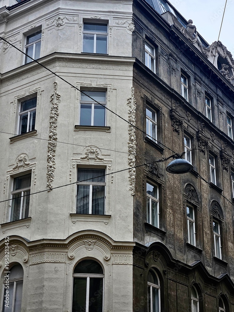 Fototapeta premium Old architecture buildings in Vienna, Austria. View of the corner of the building and the hanging lantern on the wires. The junction of the building's different colors is white and black.