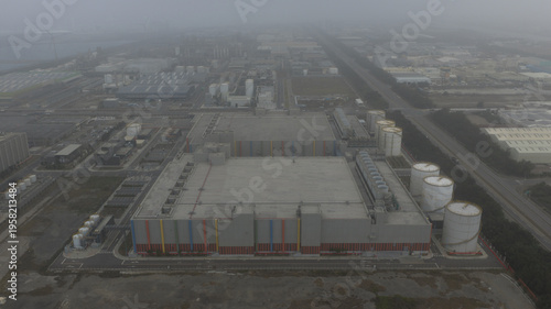 Aerial view of an industrial complex shrouded in a hazy atmosphere, its muted tones contrasting with the occasional vibrant color, Changhua, Changhua County, Taiwan.
