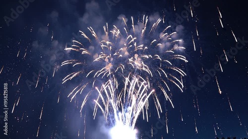 Brilliant white fireworks explode, showering dazzling light trails across the deep blue night sky, creating a grand, festive atmosphere. This spectacular display illuminates the evening with
