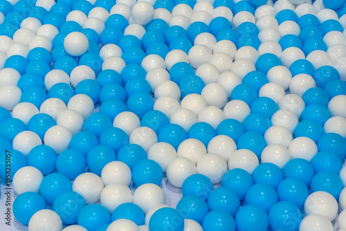 A background texture of many blue and white plastic balls in a ball pit playground.