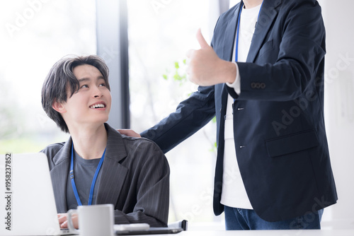 Photography 会社の仕事中に上司に励まされる新卒などの新入社員の爽やかなイメージ　その調子！仕事頑張ってね！OJTで先輩に指導を受ける若手社員の成長と教育のビジネスシーン