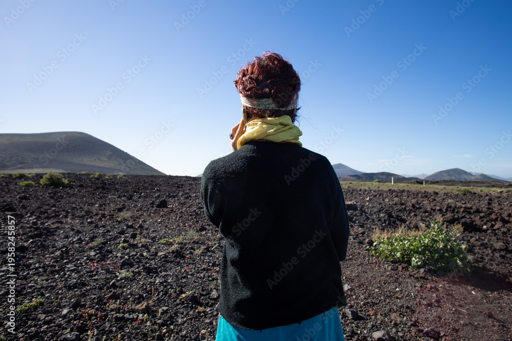Obraz premium A woman seen from behind, in a half-length shot, as she is on the phone and looking out towards the horizon.