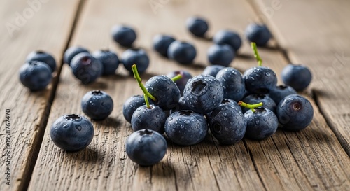 Fresh blueberries scattered on rustic wooden surface with water drops and stems closeup view of ripe forest berries for healthy nutrition and vegan breakfast