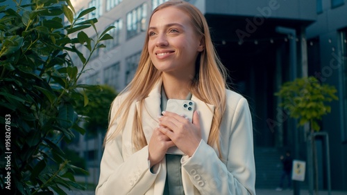 Smiling happy Caucasian businesswoman reading good news on smartphone outdoors female business woman lady enjoying message browsing social media online receiving email hugging mobile phone street city