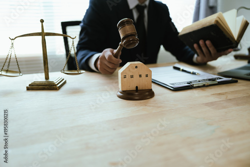 Judge holding gavel over a house model with legal documents, symbolizing real estate law, property disputes, and housing regulations.