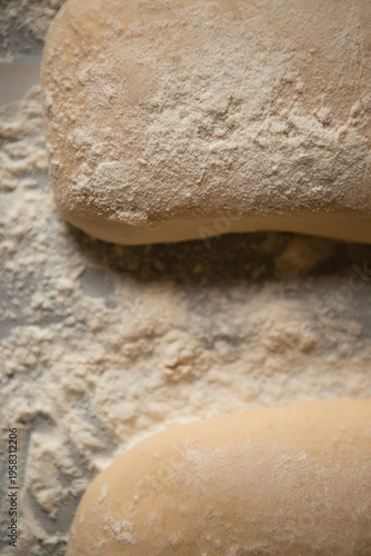 Close-up of raw ciabatta dough generously dusted with flour on a baking surface before going into the oven. Artisan bread preparation process, rustic style, soft natural lighting.