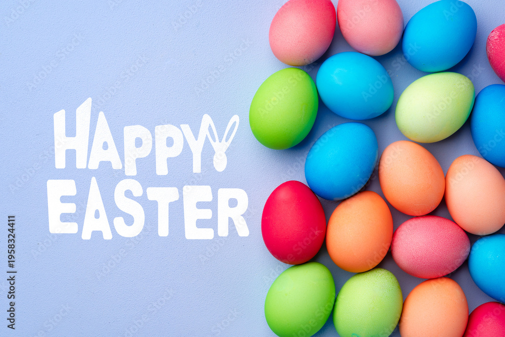 Fototapeta premium Bright colored eggs and a greeting for Easter celebration on a blue background