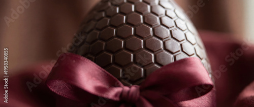Chocolate easter egg with honeycomb pattern and red ribbon