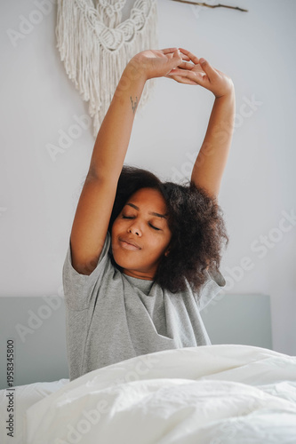 Quadro em tela relaxed woman stretching in bed with eyes closed after restful sleep