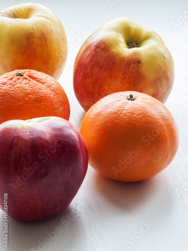 Group of colorful fresh fruits on table, ripe oranges citrus and apples on white background.