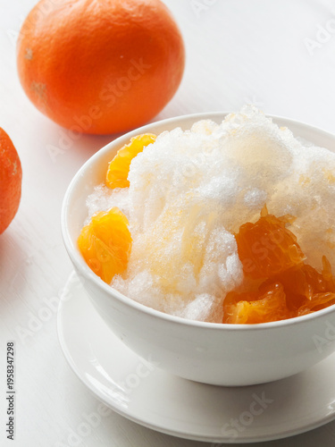 Shaved ice Kakigori granita fruit dessert for summer made of ice with juice sauce in bowl on table.