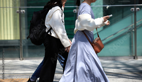 春の昼の都市の繁華街で歩く若い女性観光客の姿