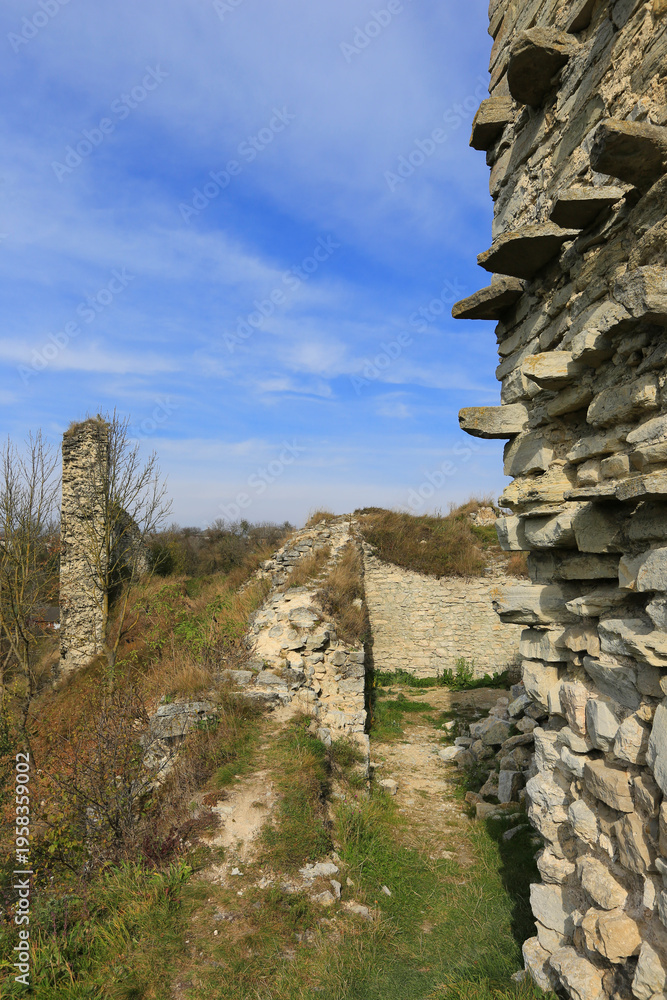 Fototapeta premium Ancient stone ruins on a hill under a bright blue sky with wispy clouds