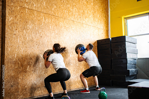 Obraz na plátně Two people doing wall ball squats during fitness workout