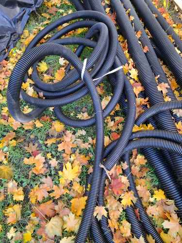 Black plastic corrugated pipes lie on the ground