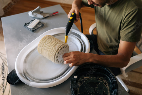Tableau sur toile Top view of man cleaning humidifier filter using steam cleaner, removing dust an